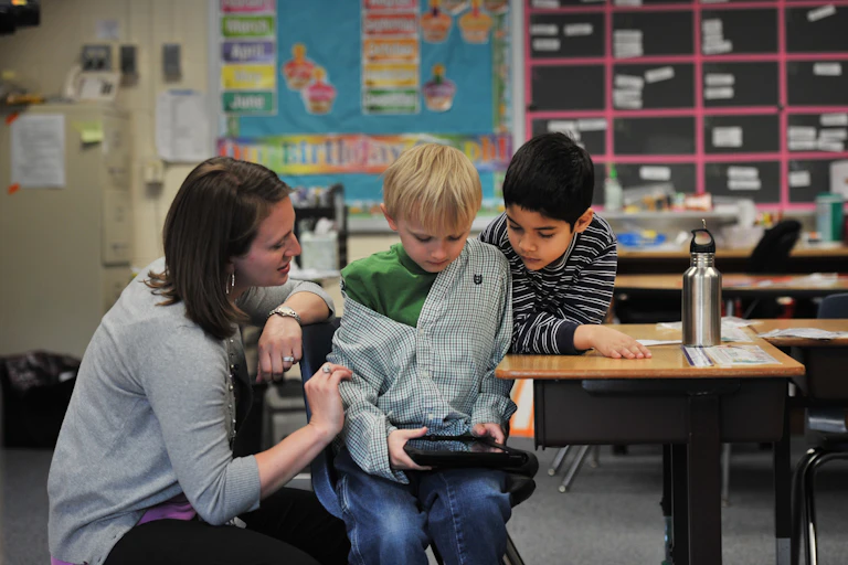 A special education teachers uses an iPad to communicate with an autistic child.