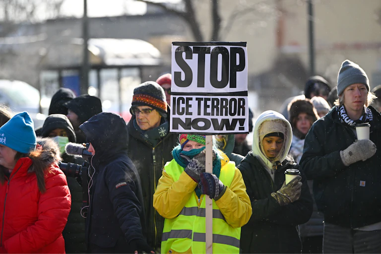 Una mujer sostiene un cartel con el lema "¡Acabemos con el terror de ICE ya!" en un acto conmemorativo por Alex Pretti.