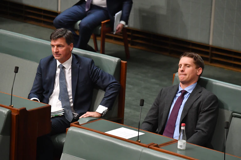 Two men in suits sit in the house of representatives