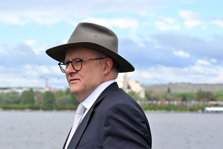 Prime Minister Anthony Albanese, in an akubra hat and suit, looking thoughtful in front of water