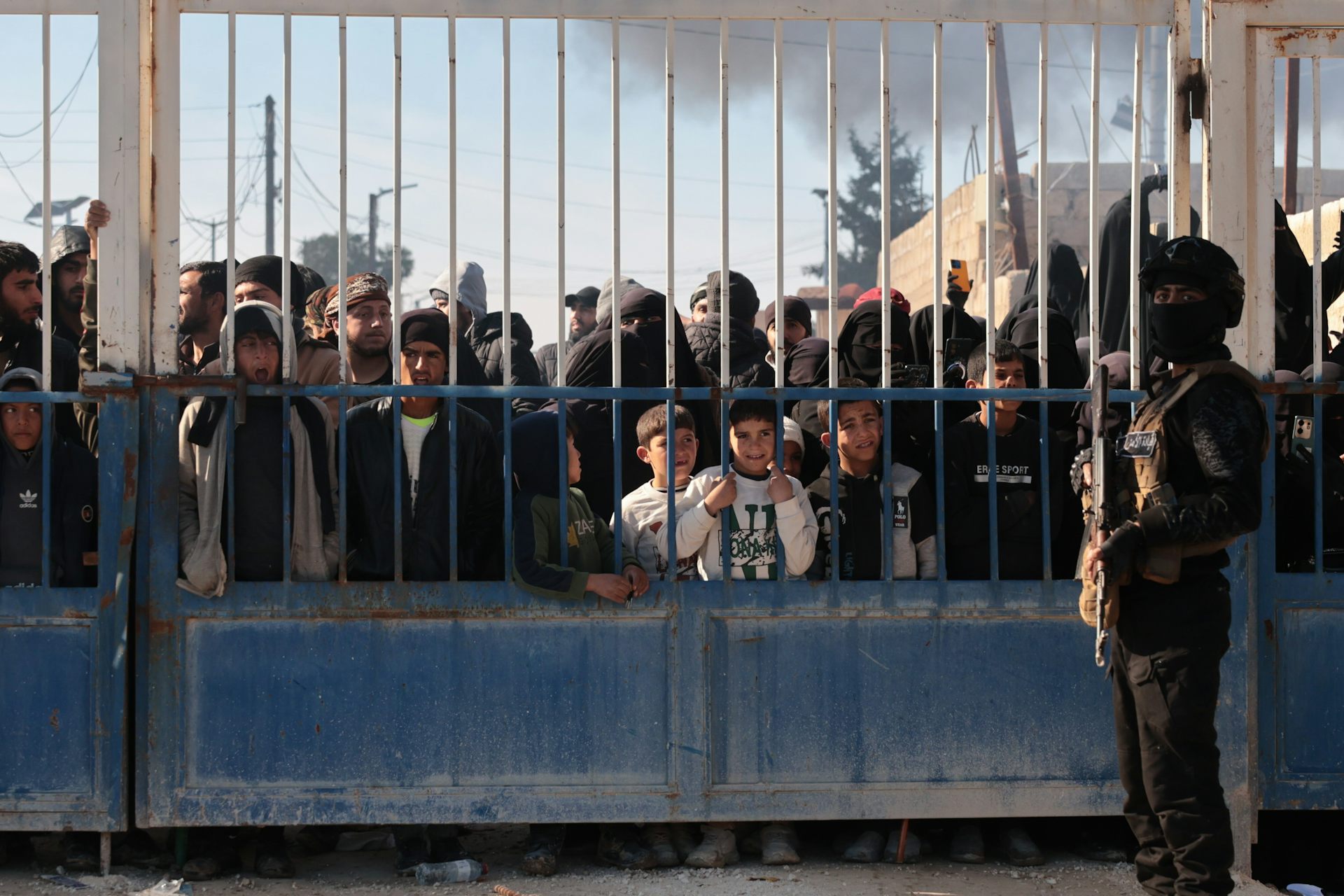 A Syrian security member stands guard outside the gates of the Al-Hol detention camp.