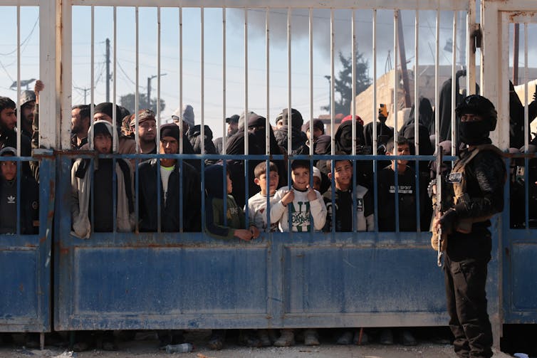 A Syrian security member stands guard outside the gates of the Al-Hol detention camp.