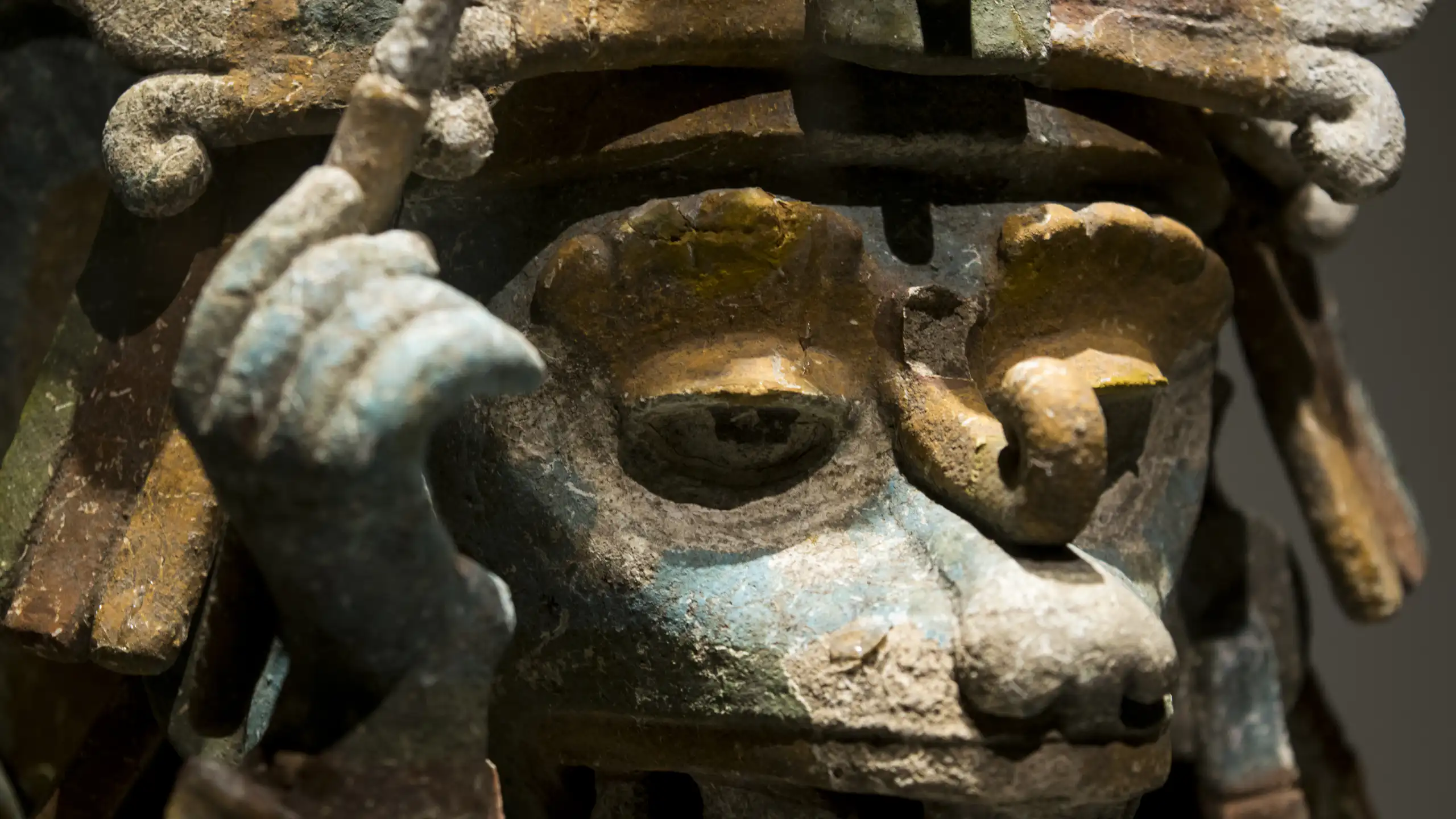 Escultura de un animal con un tocado y sosteniendo un últil de escritura.