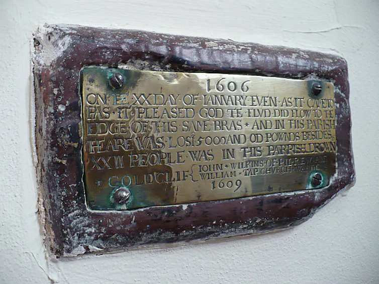 An old brass plaque on wood commemorating the event.