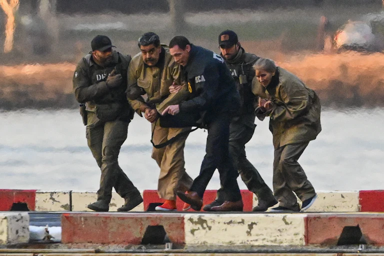 US drug enforcement agents escort Venezuelan president, Nicolás Maduro, and his wife, Cilia Flores, from a helicopter on a dickside.