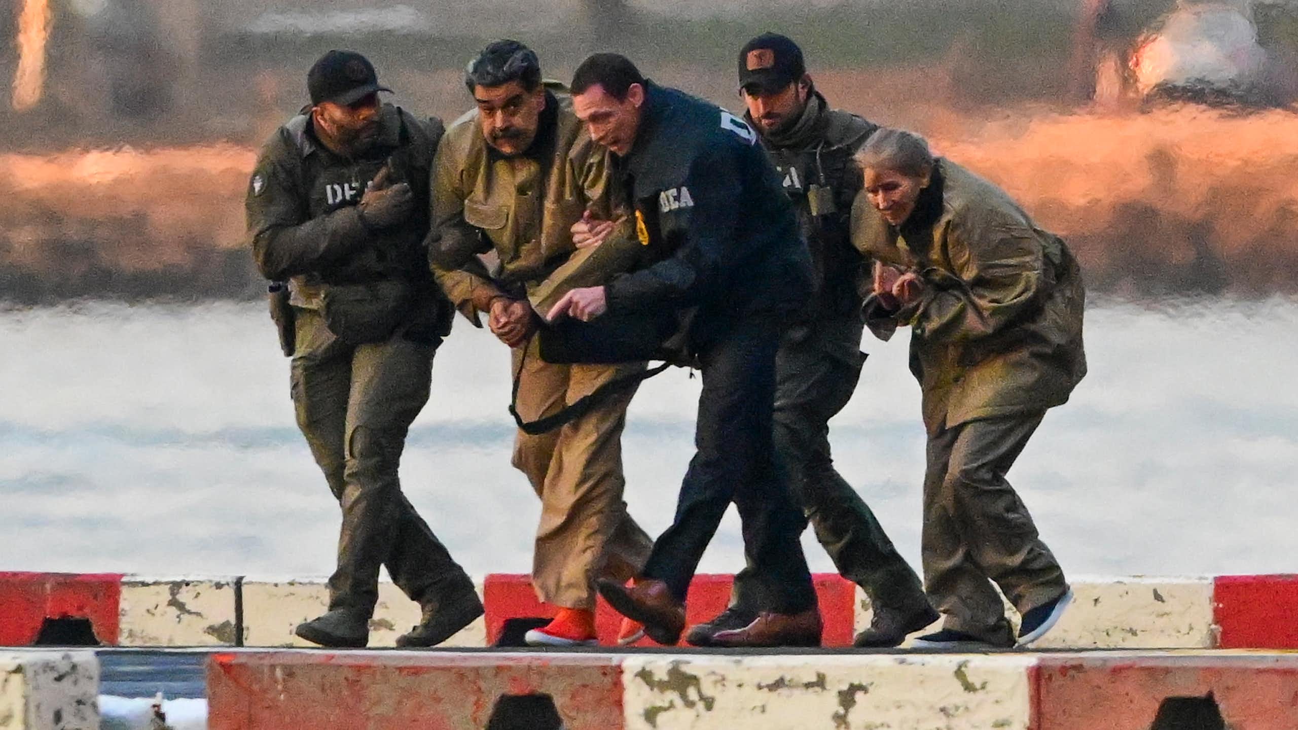 US drug enforcement agents escort Venezuelan president, Nicolás Maduro, and his wife, Cilia Flores, from a helicopter on a dickside.