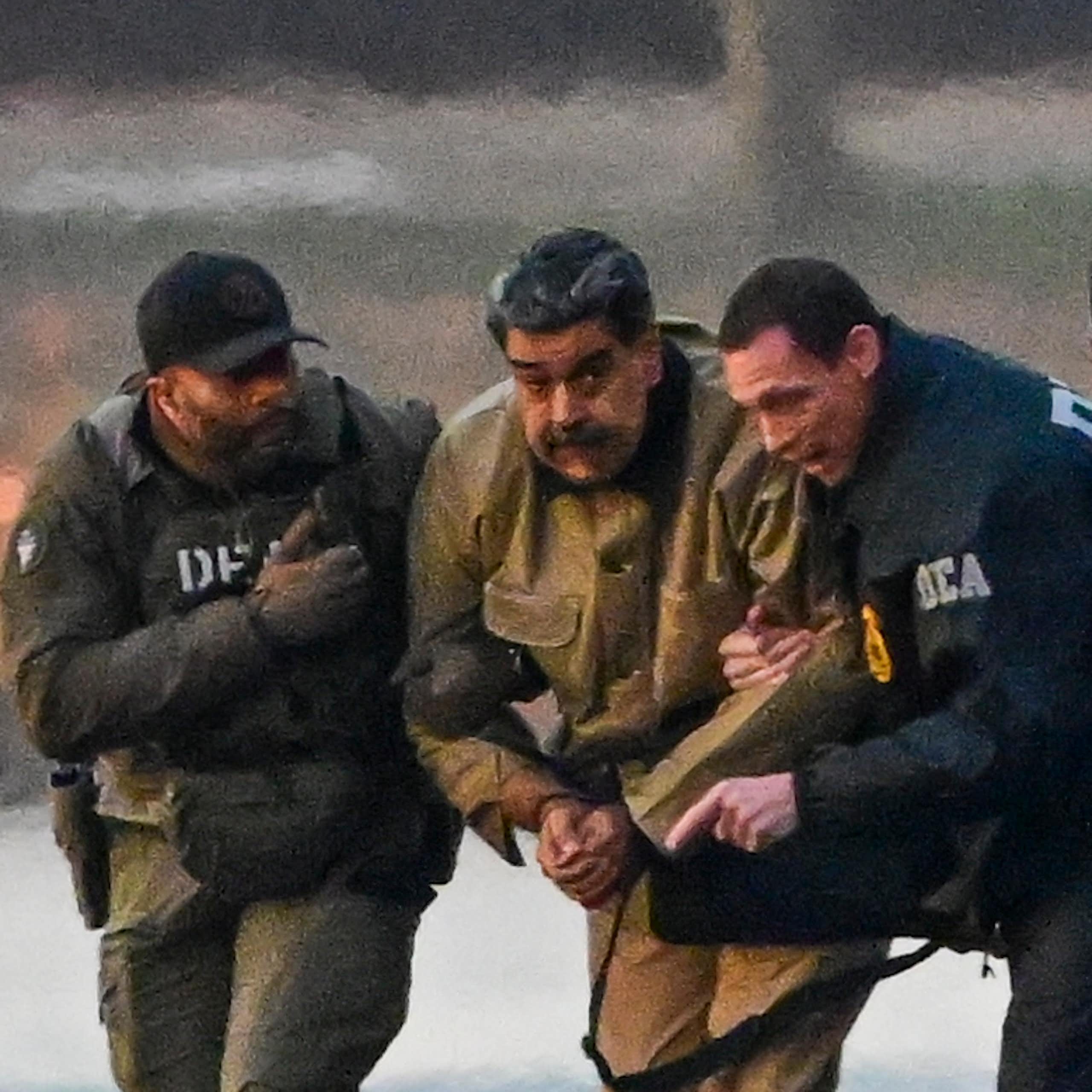 US drug enforcement agents escort Venezuelan president, Nicolás Maduro, and his wife, Cilia Flores, from a helicopter on a dickside.