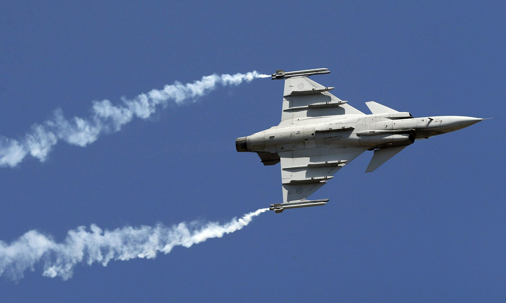 A fighter jet with contrails at an air show.