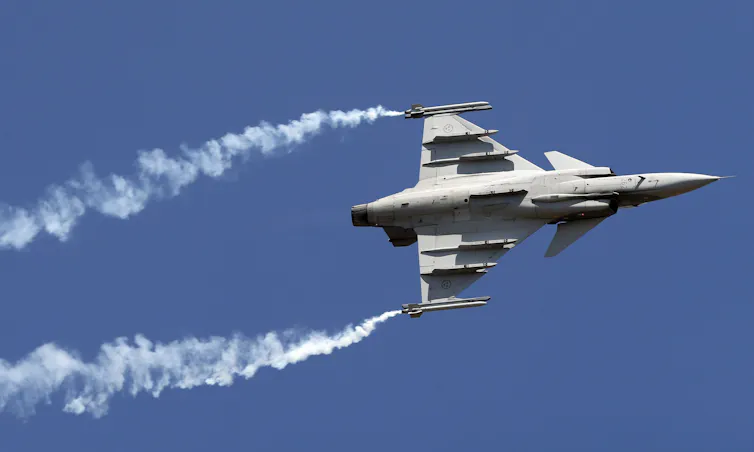 A fighter jet with contrails at an air show.