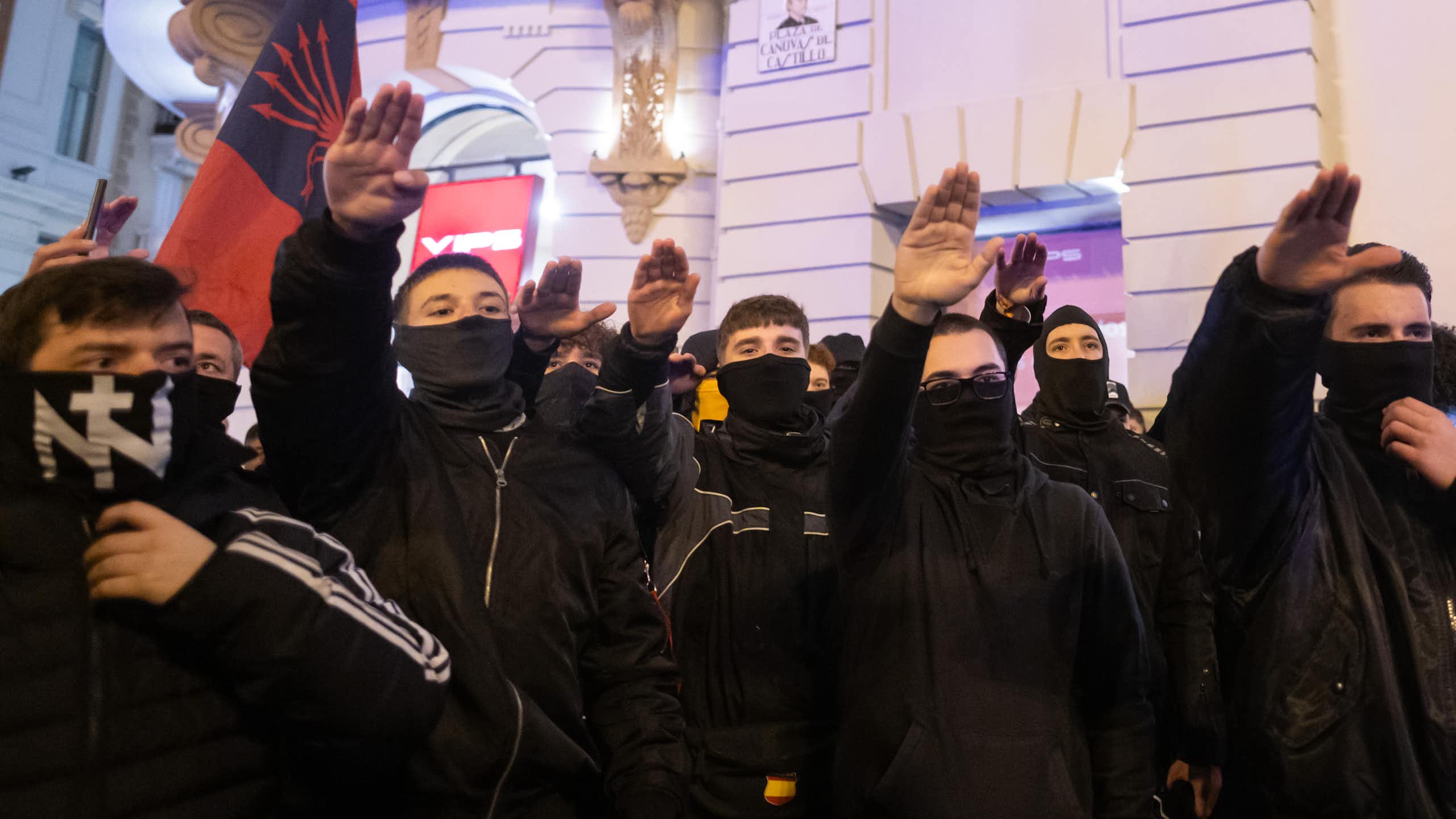 Protesters covered in black make a fascist salute at a protest in Madrid.