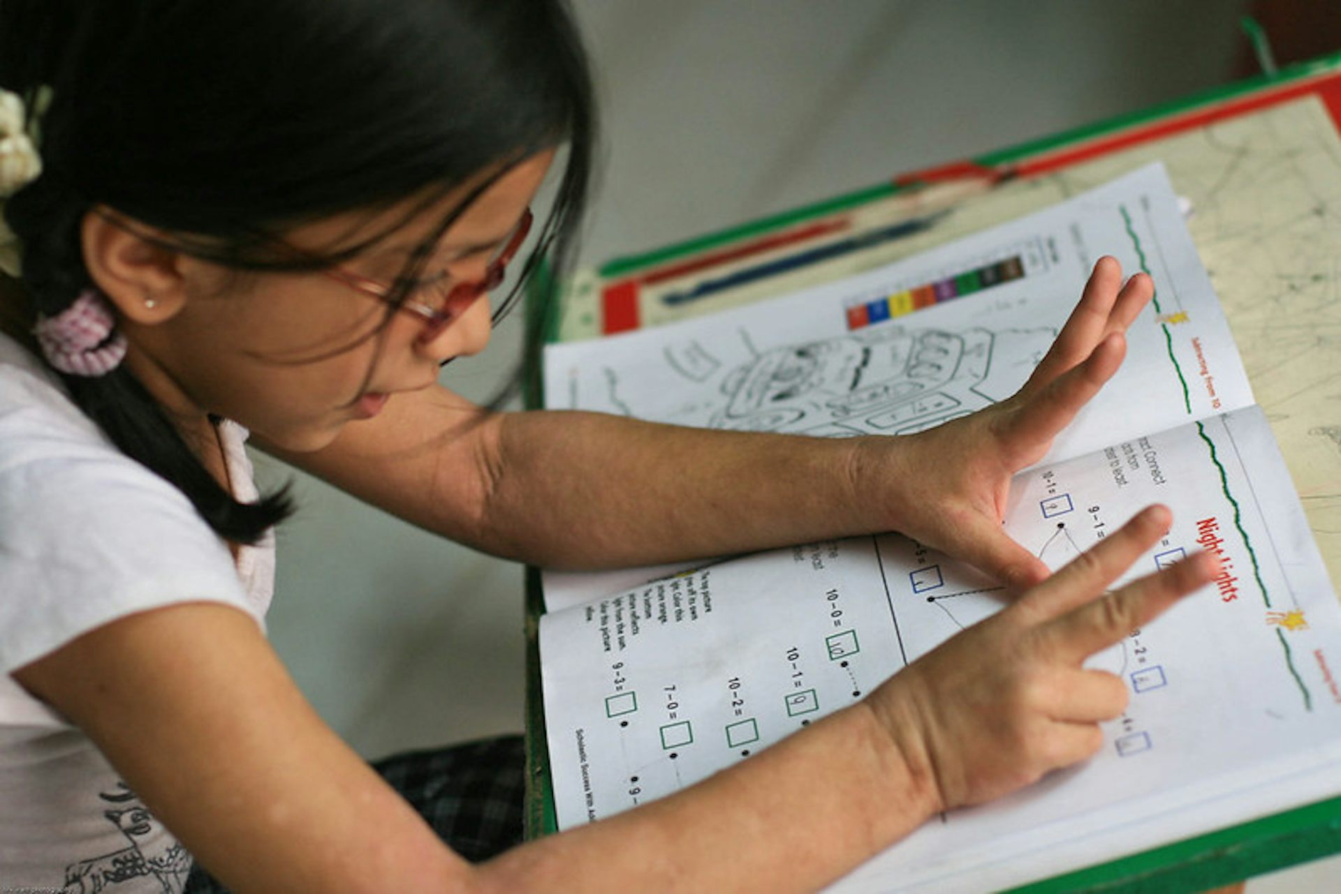 A child at a desk looking happy doing work.