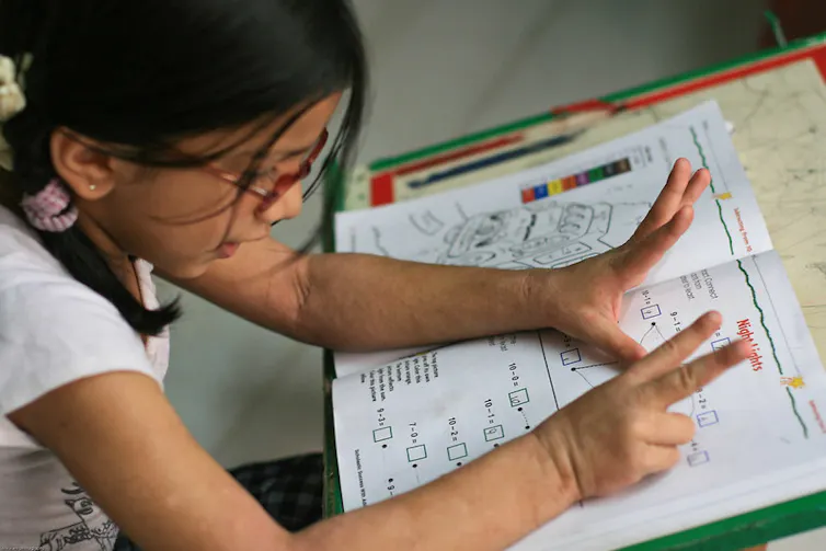 A child at a desk looking happy doing work.