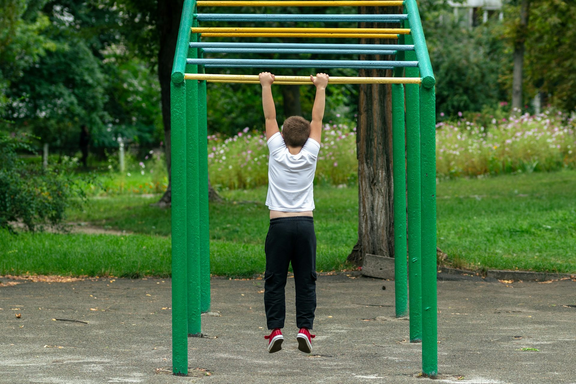Un niño cuelga de unas barras en el parque.