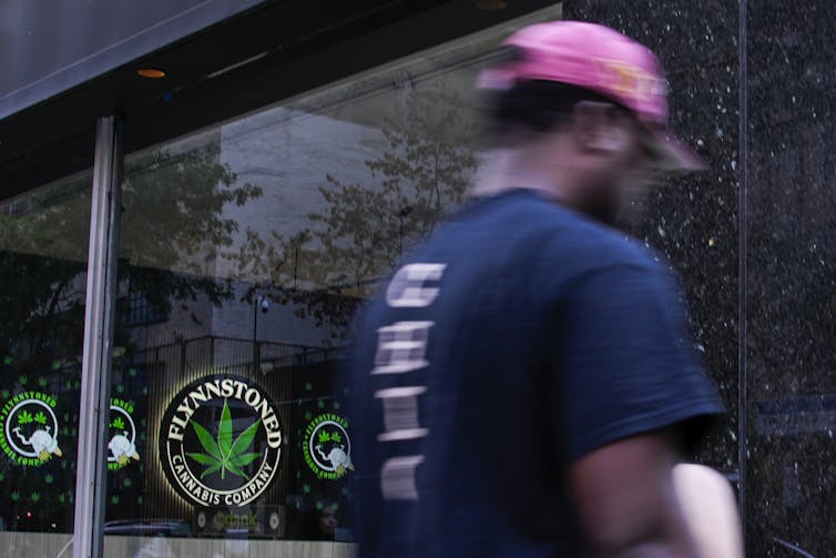 A man in a pink hat walks past a glass-front building.