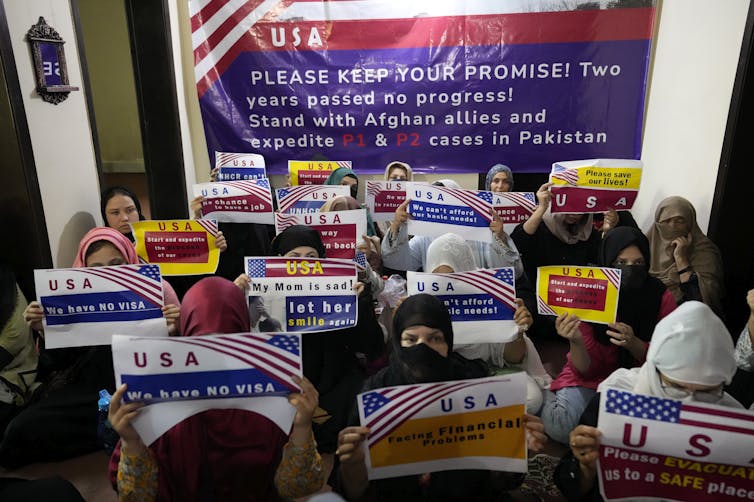 Several women in a room hold placards.
