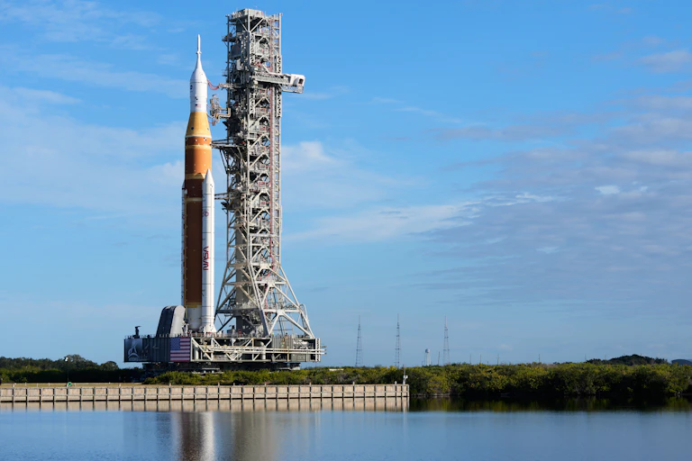 A tall rocket, with multiple stages and two boosters, on a launchpad.