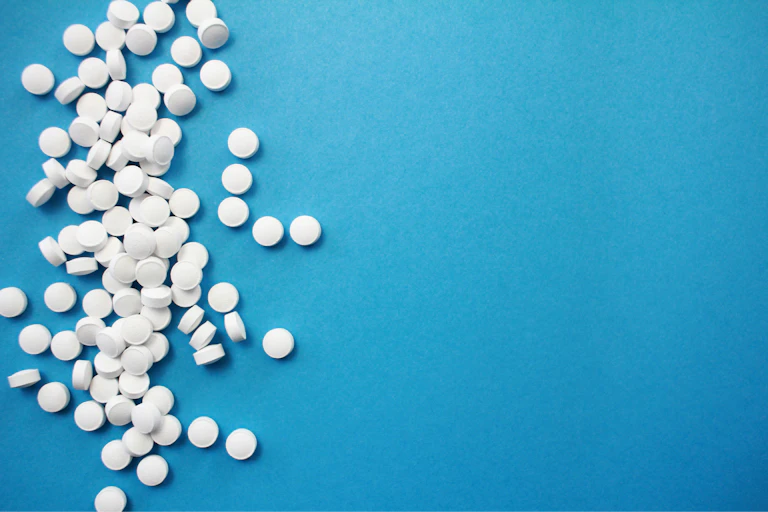 White tablets piled on the left side of a blue background