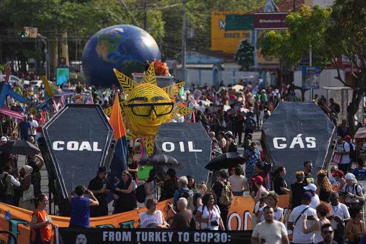 protestors carrying coffins with the words coal oil and gas on them.