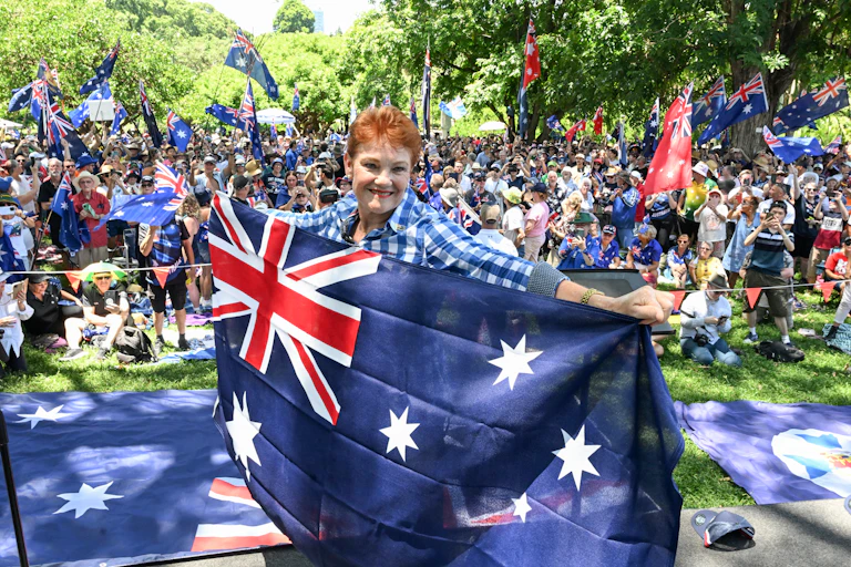 Pauline Hanson smiles while holding an Australian flag