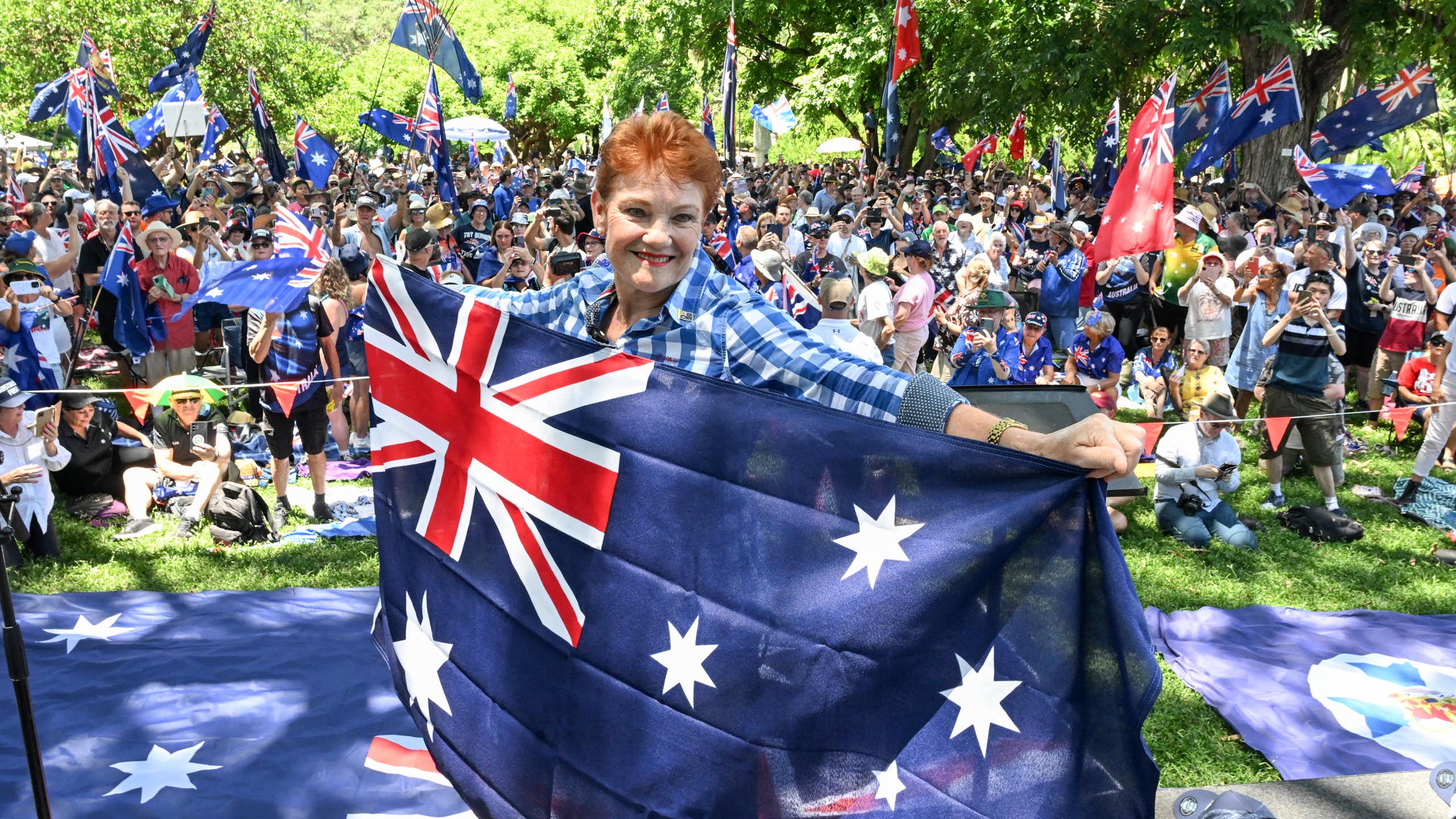 Pauline Hanson smiles while holding an Australian flag
