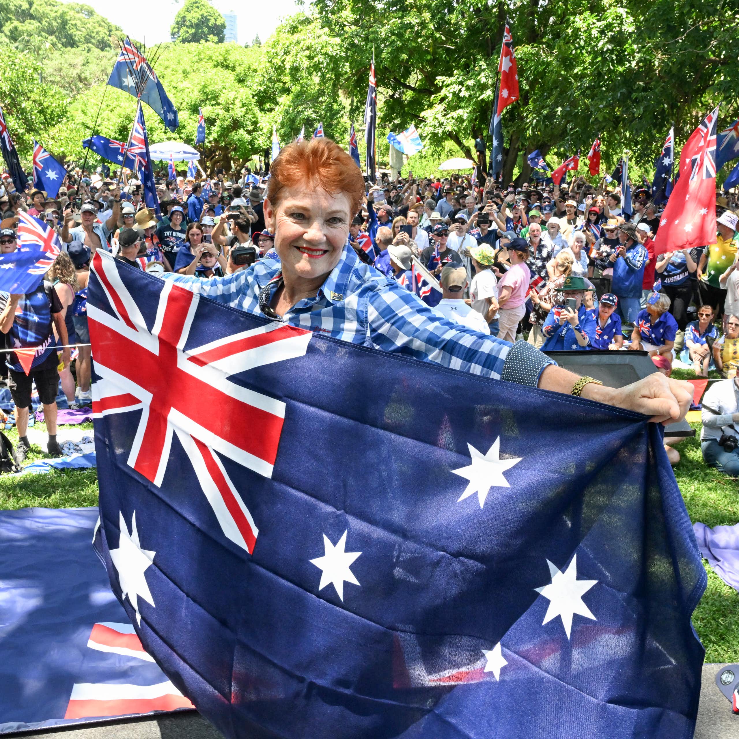 Pauline Hanson smiles while holding an Australian flag