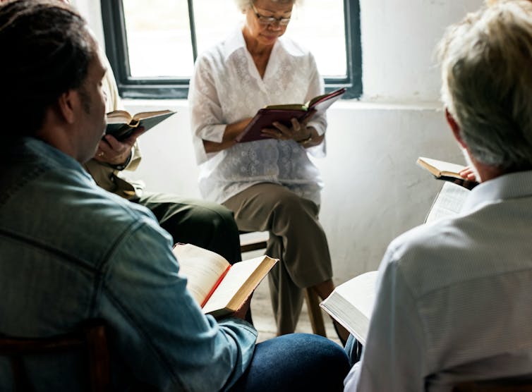 People sitting in a circle have books on their laps