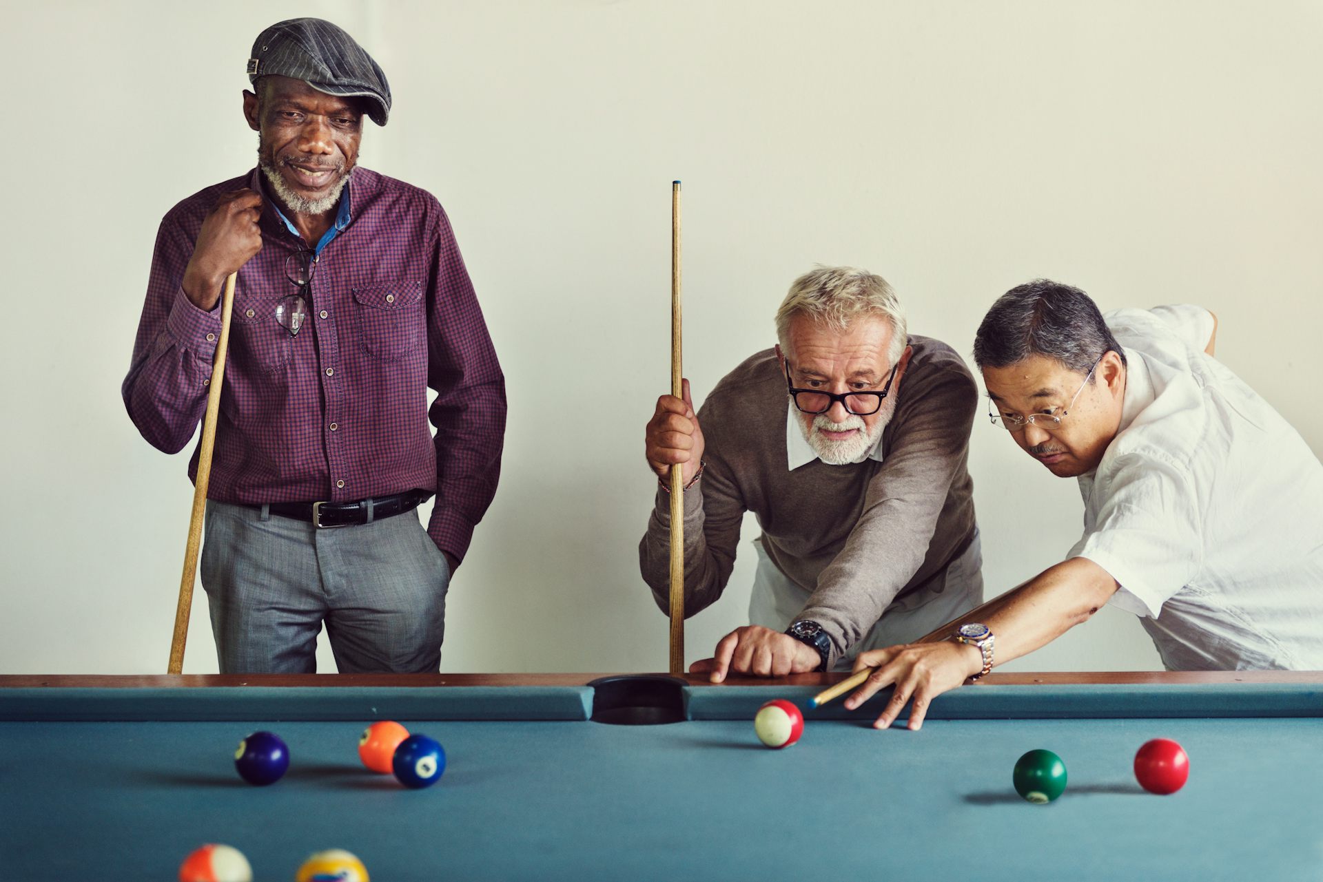 Three older men playing billiards