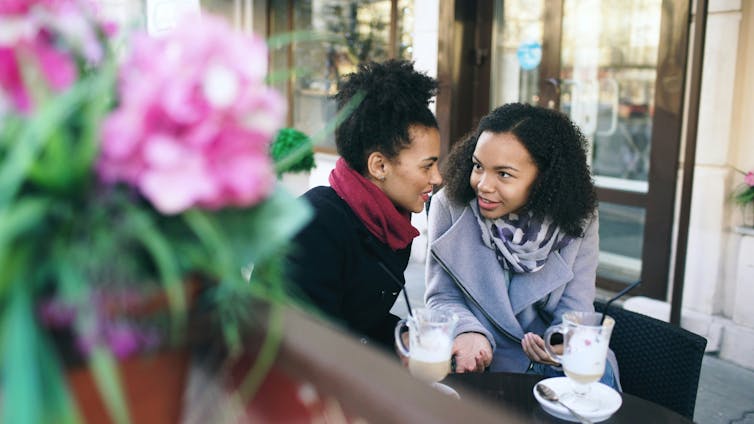 Two young women in winter clothes in a cafe