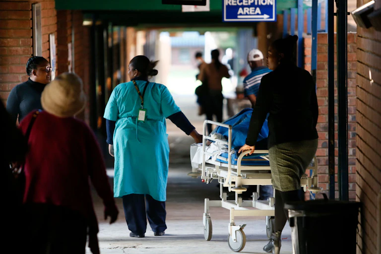 People pushing a mobile hospital bed in a corridor