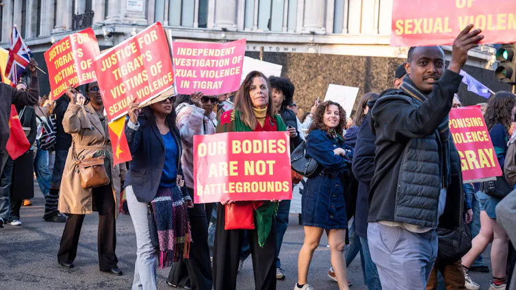 Women protest in London, holding banners highlighting the use of sexual and reproductive violence against women in Ethiopia.