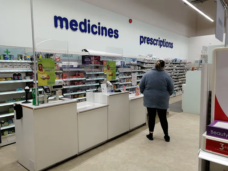 A person stands at a pharmacy counter.