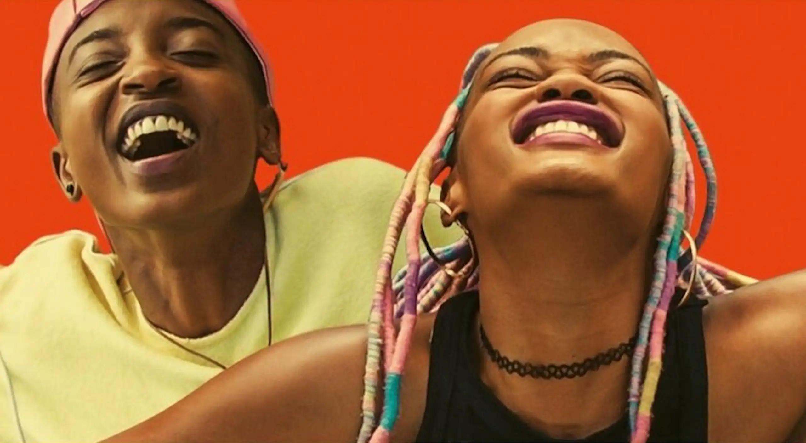 An illustration of a photo with a bright red background, showing two young women smiling broadly.