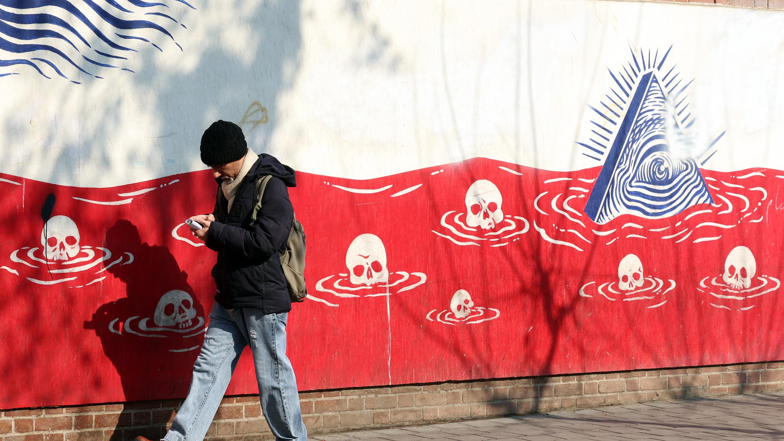 A man walks past an anti-US mural in Iran