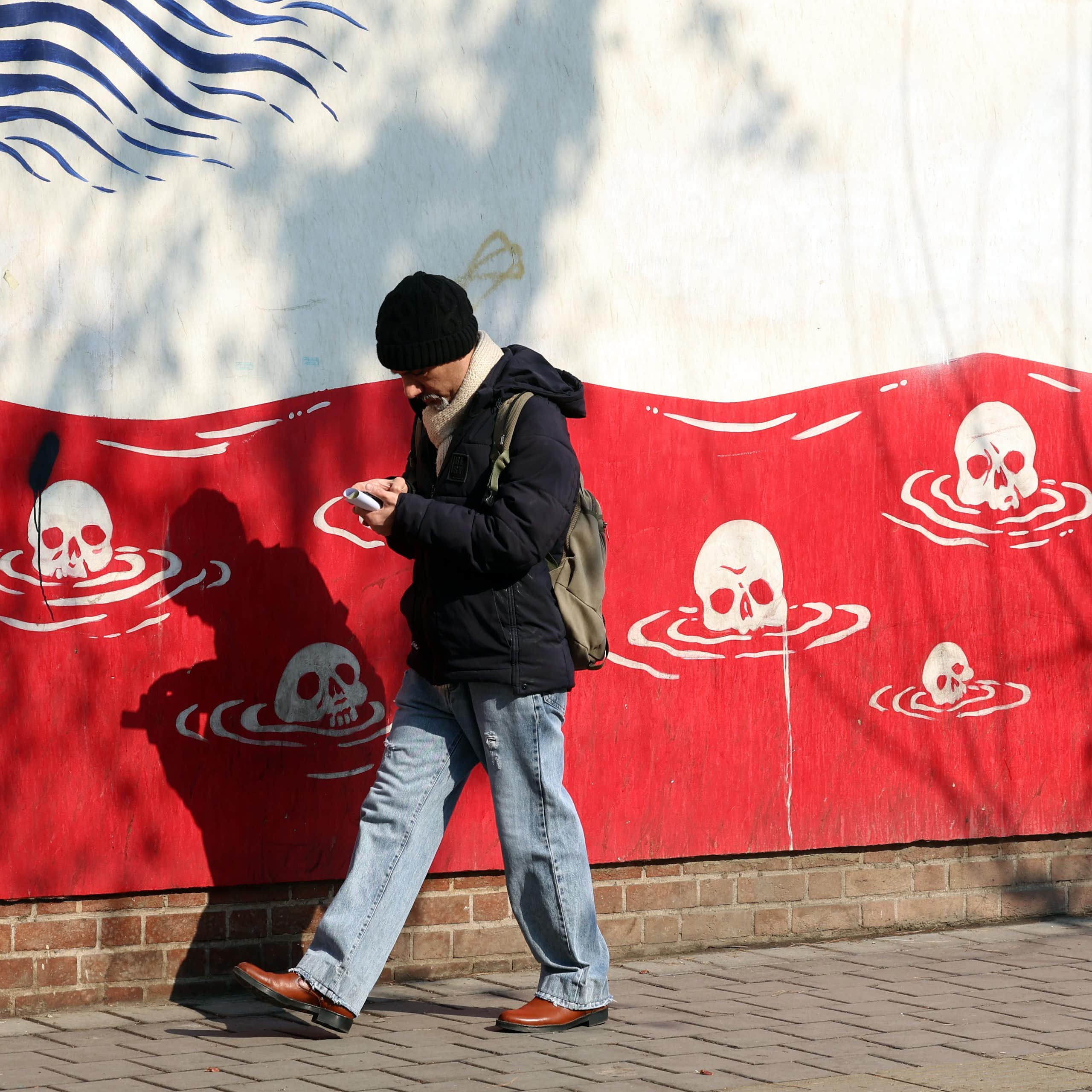 A man walks past an anti-US mural in Iran