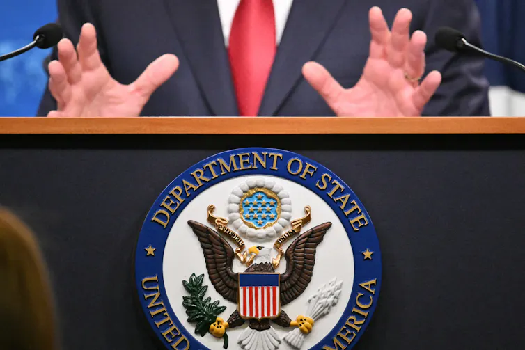 A man's hands rest on top of a podium.