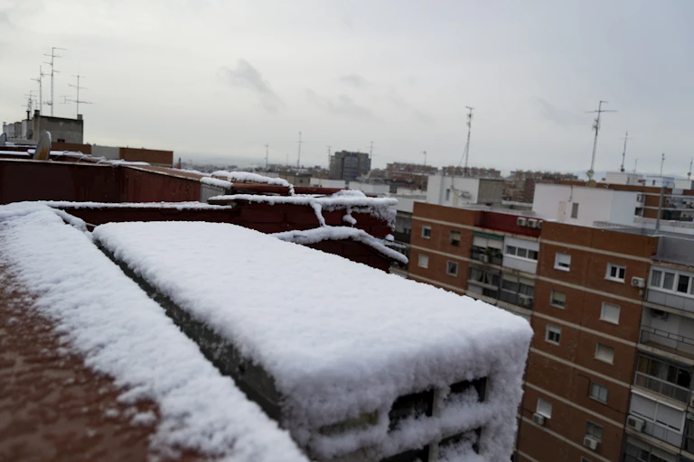 Nieve sobre la azotea de edificios de ladrillo rojo.