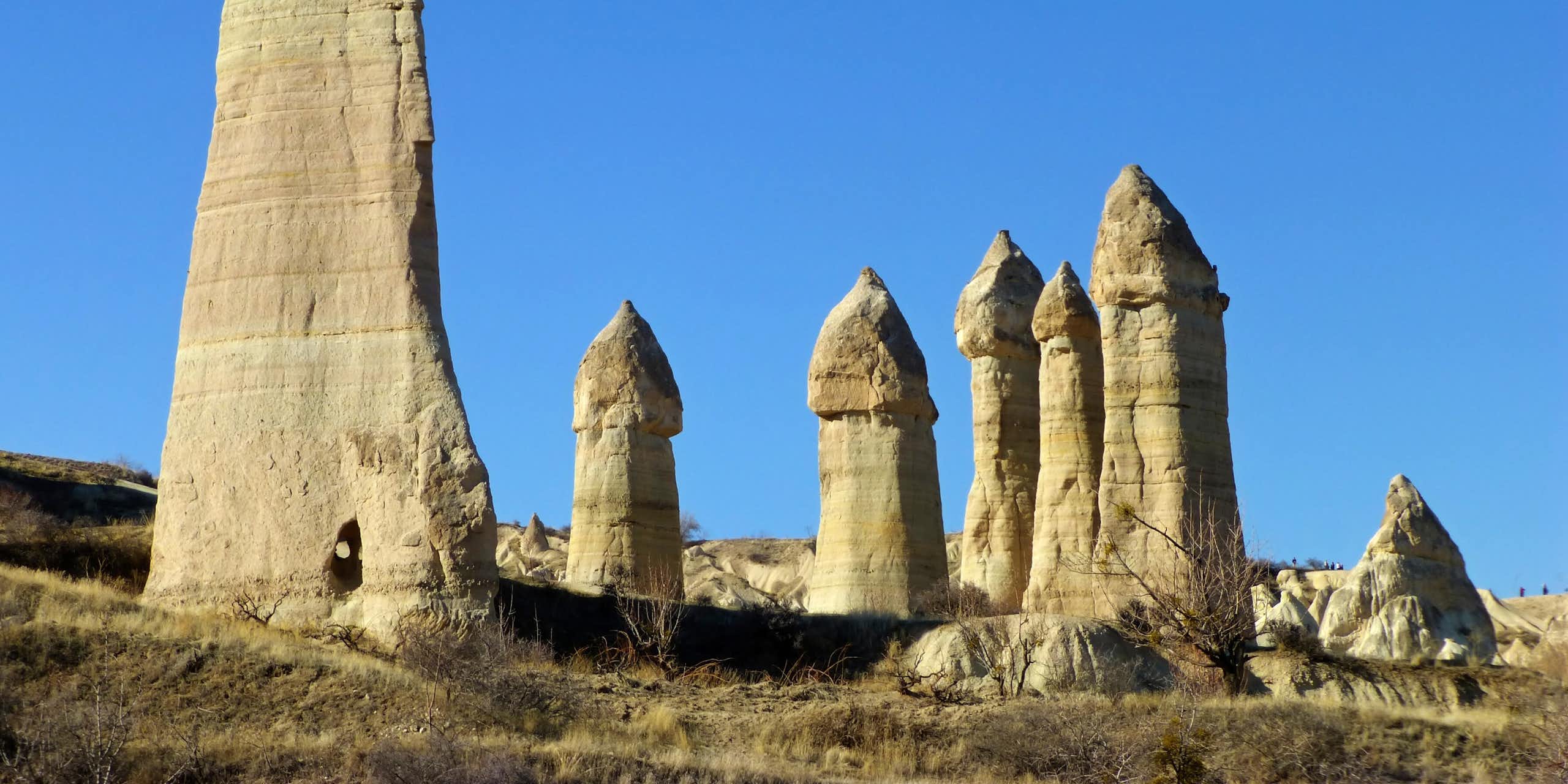 Une série de formations rocheuses phalliques se détachant sur un ciel bleu.