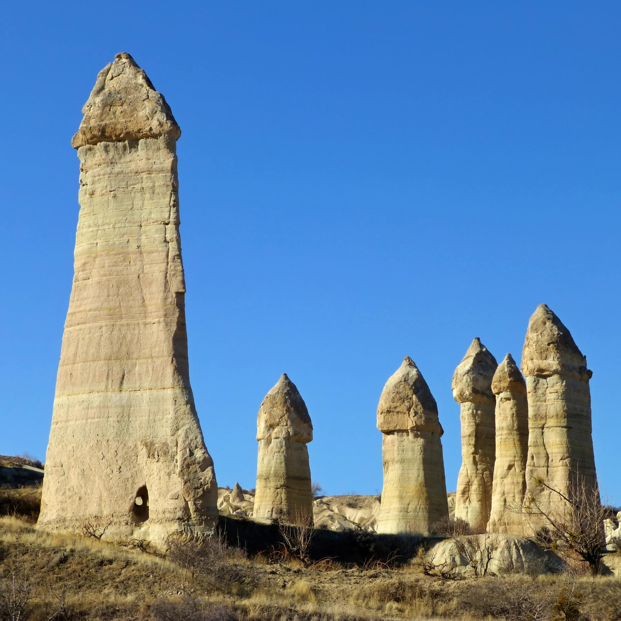 Une série de formations rocheuses phalliques se détachant sur un ciel bleu.