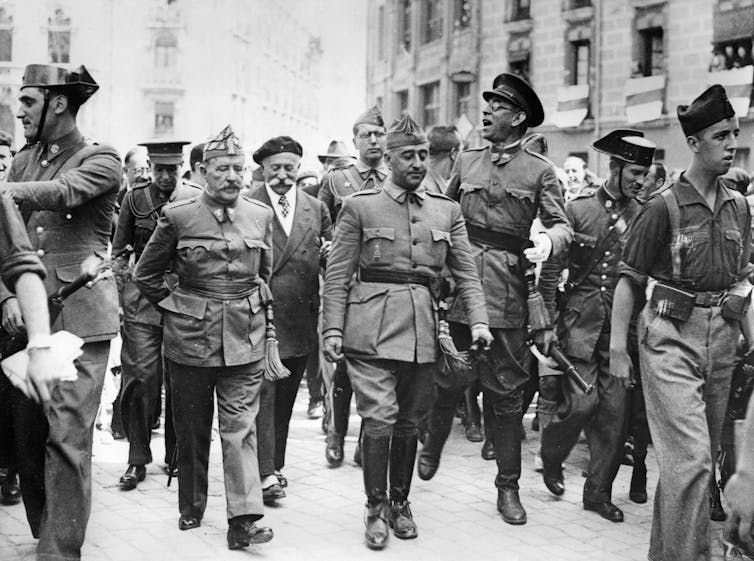 A group of men in military uniforms walking down a street.