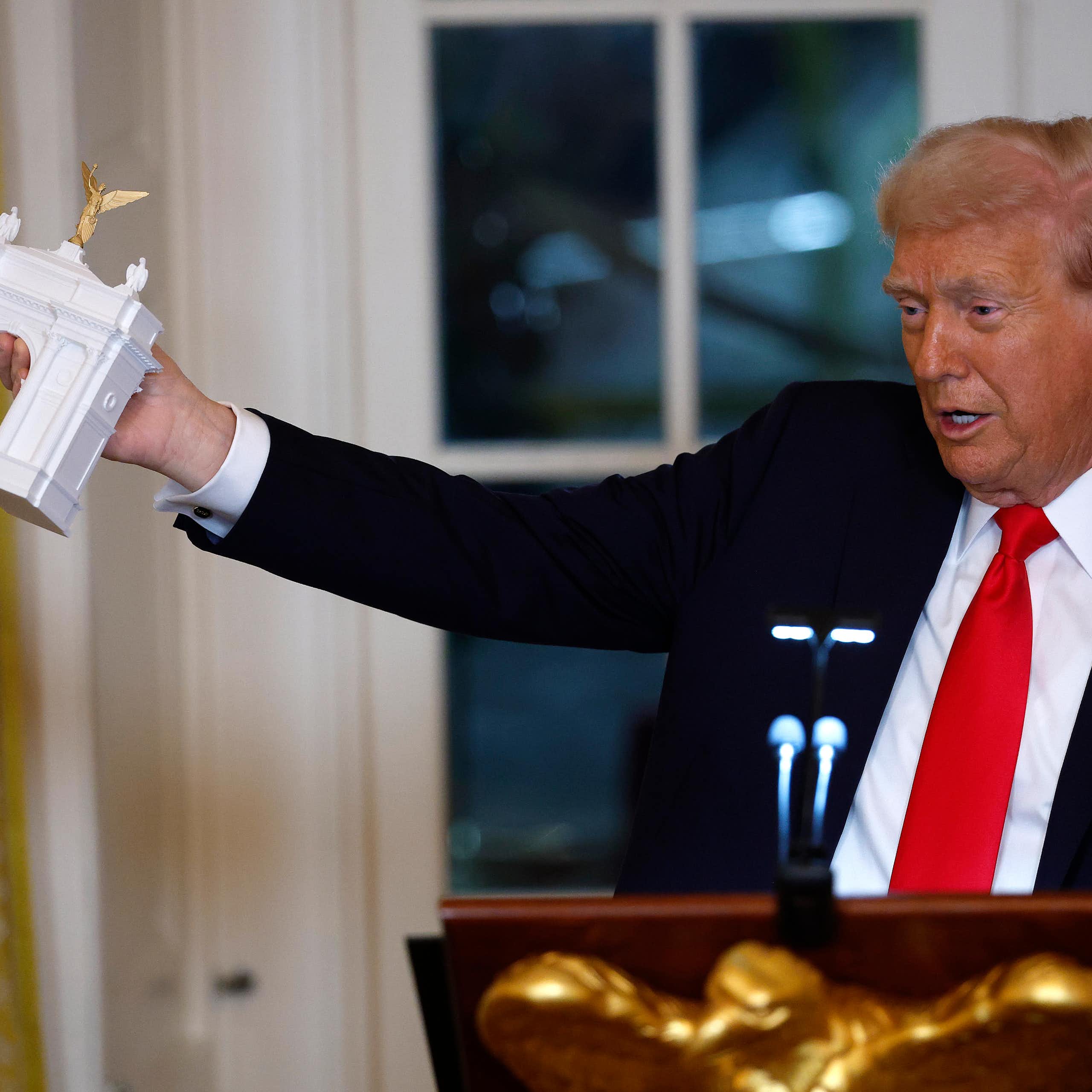 Donald Trump holding a small model of a triumphal arch