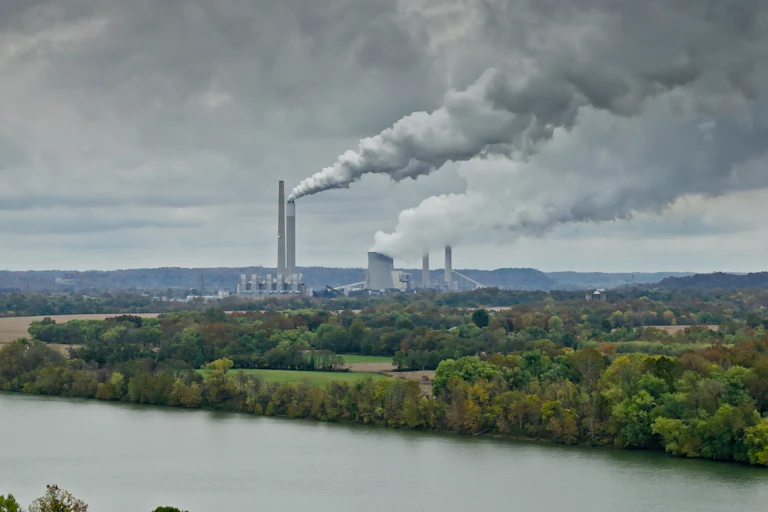 A view across the Ohio River to two coal plants, with steam rising.