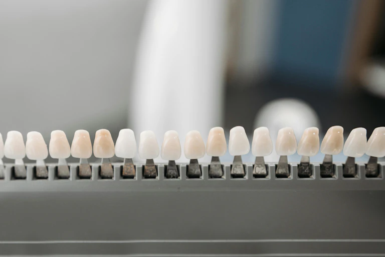 A row of teeth veneers in different shades of white and off white.