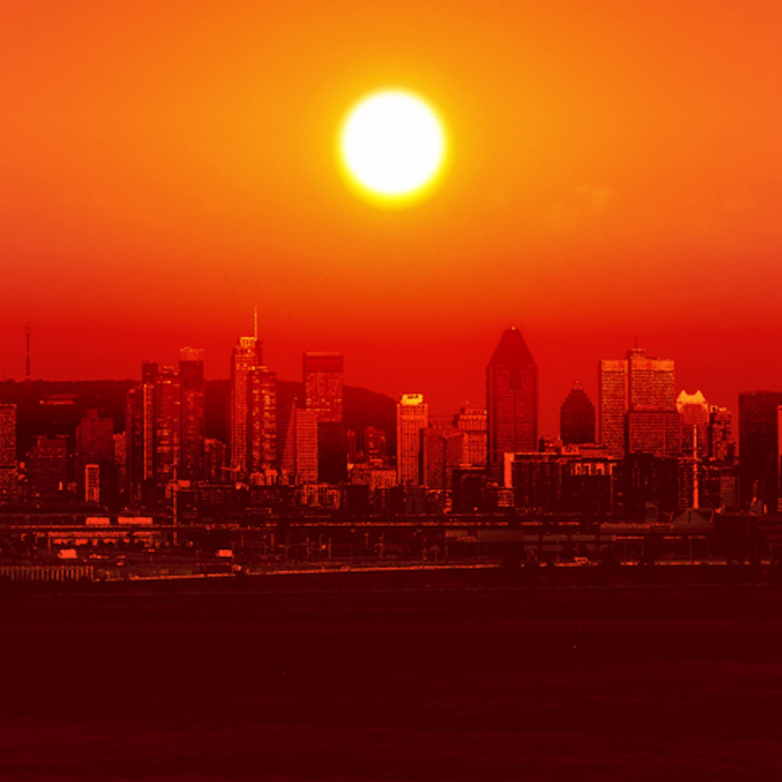 A red sun rises over a city, in an atmosphere of heat.