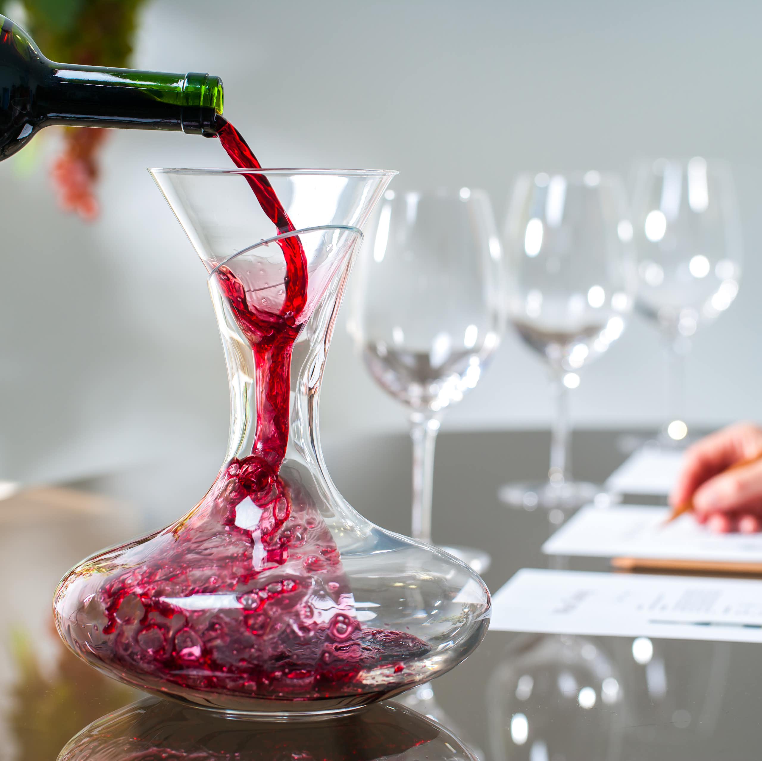 Close up of sommelier pouring red wine into decanter at wine tasting session