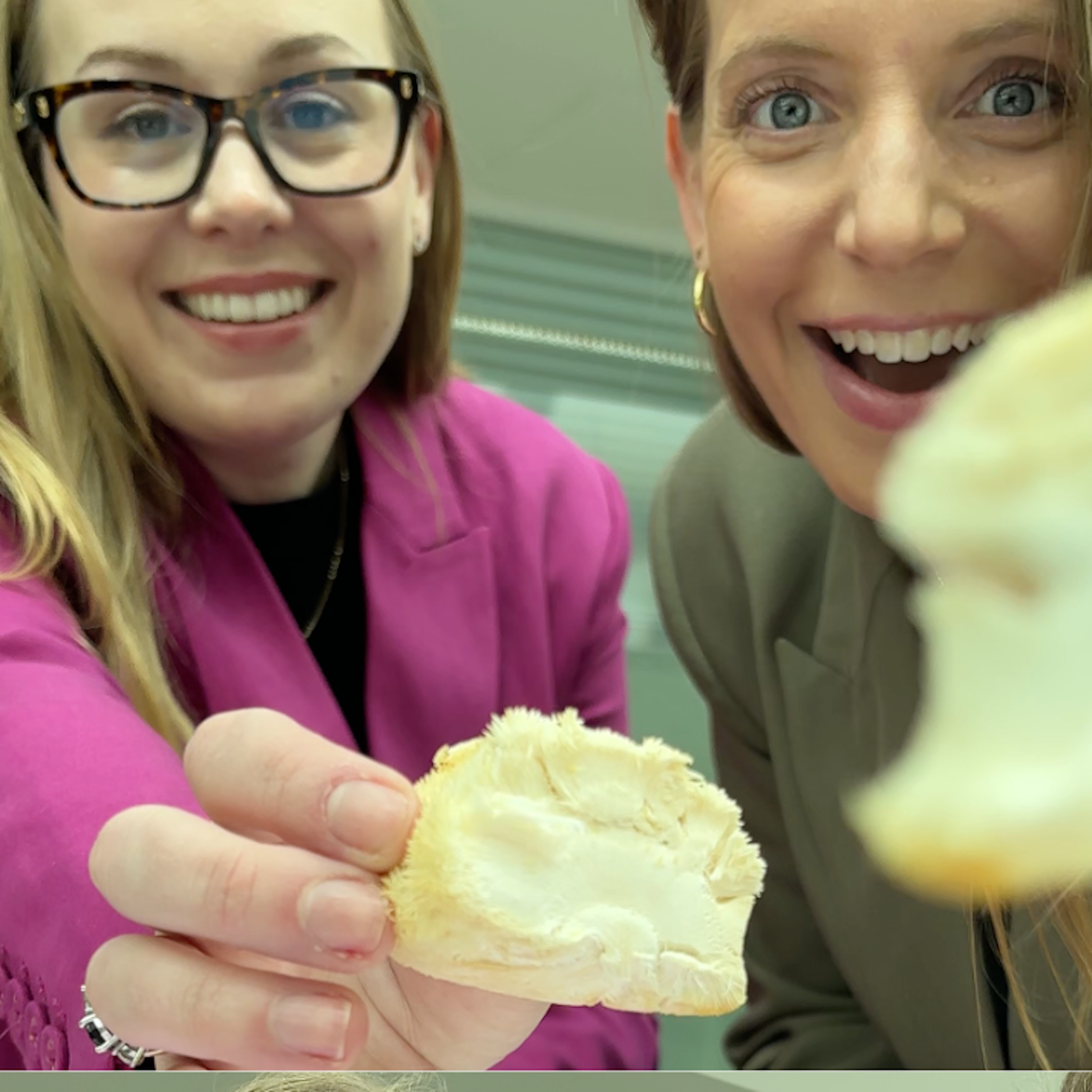 Two women happily eating mushrooms.