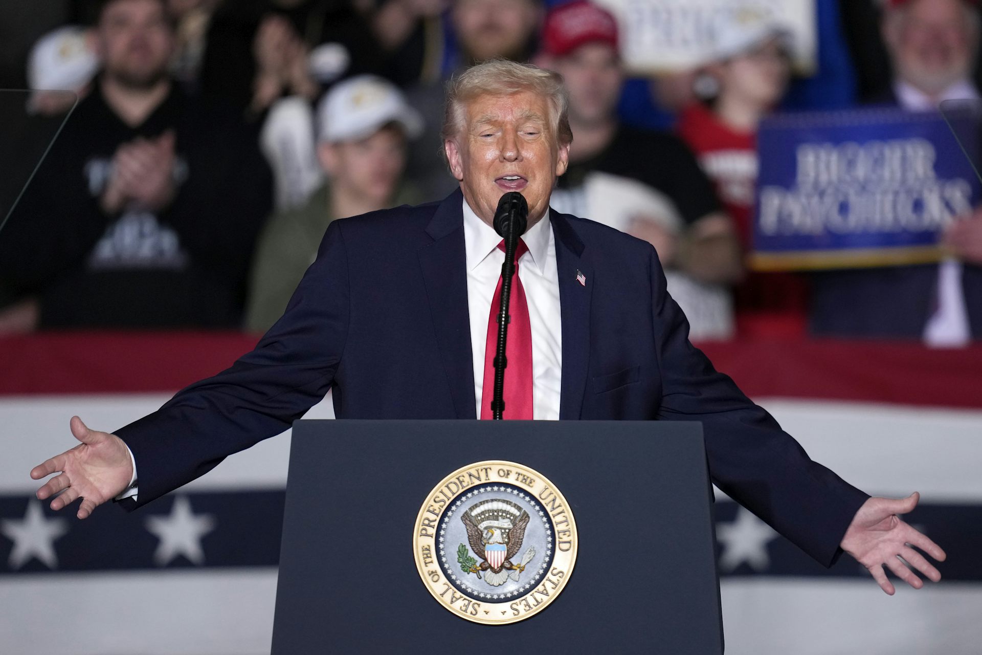President Trump at a podium, arms outstretched.