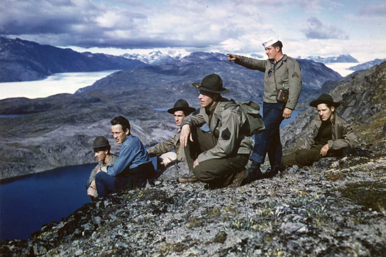 A group of American servicemen stand on top on a mountain in Greenland.