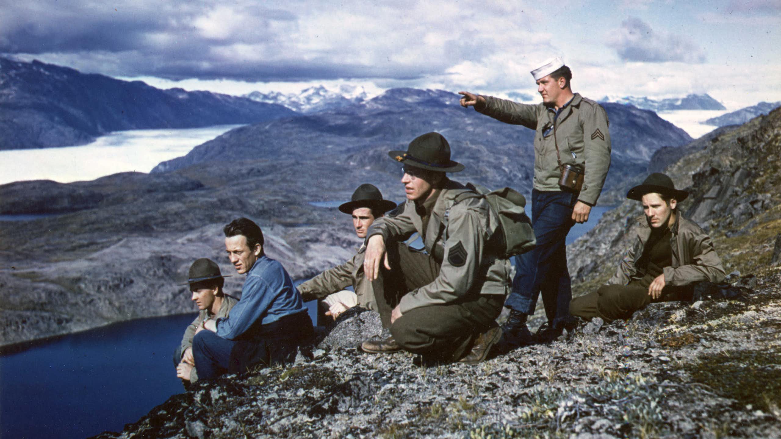 A group of American servicemen stand on top on a mountain in Greenland.