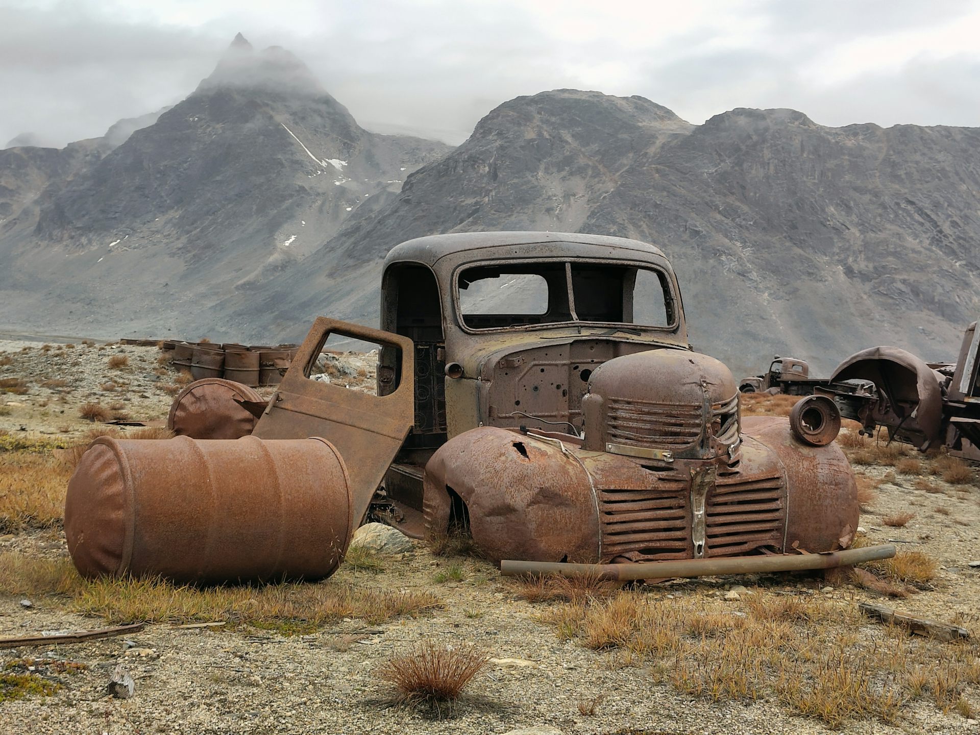 A rusting vehicle surrounded by mountains in Greenland.