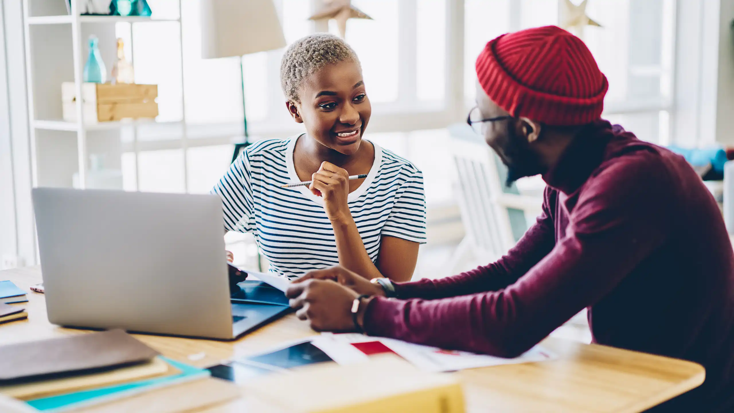 Two people talking at desk with laptop
